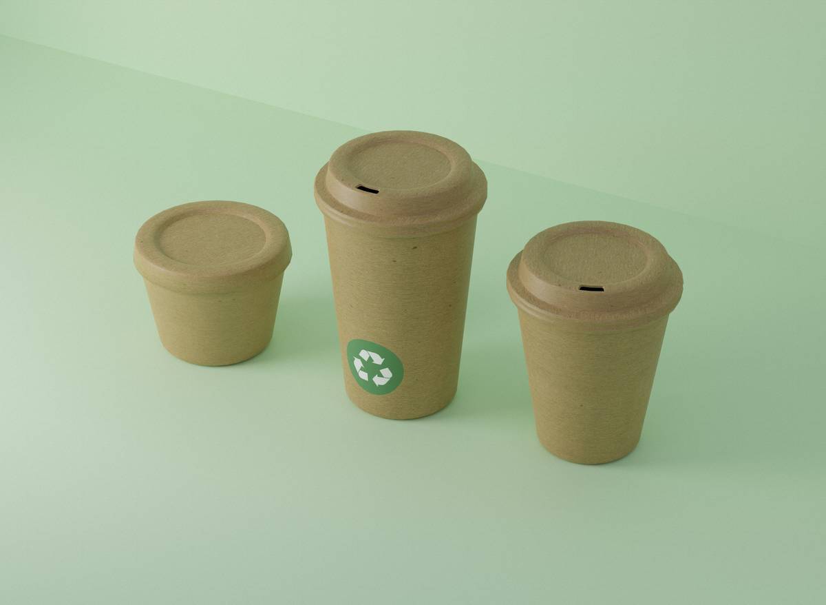 eco friendly travel coffee mug on a wooden table next to a backpack and coffee beans