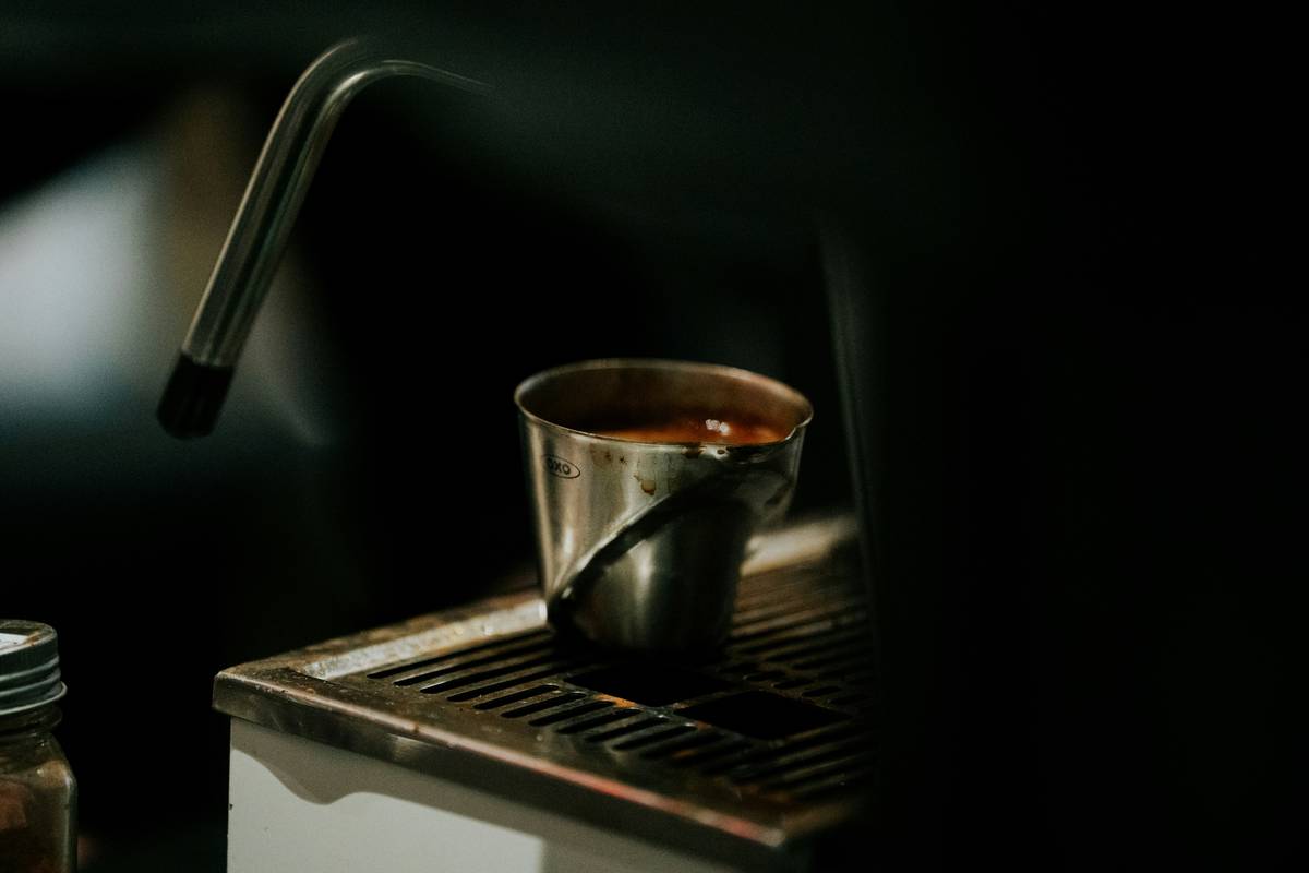 Coffee stainless steel mug on a wooden countertop with steam rising, showing double-wall design