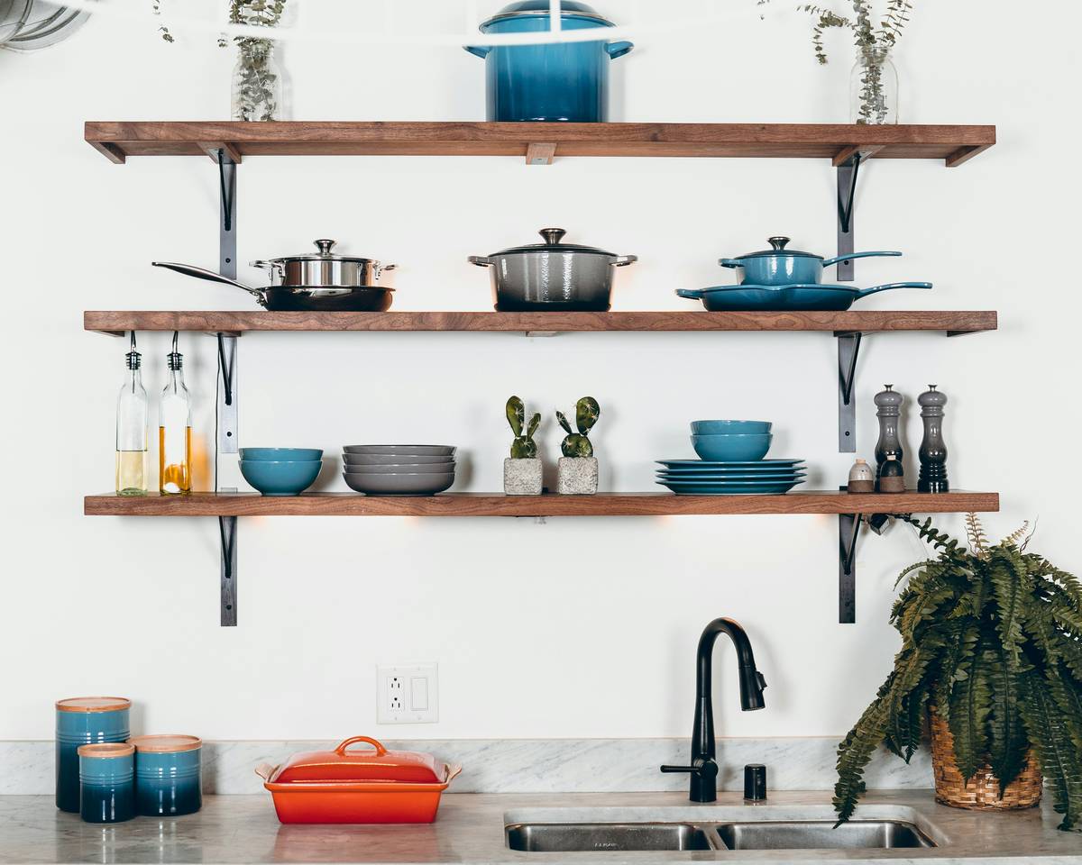 eco friendly bamboo coffee mugs on a wooden kitchen counter next to a ceramic coffee pot